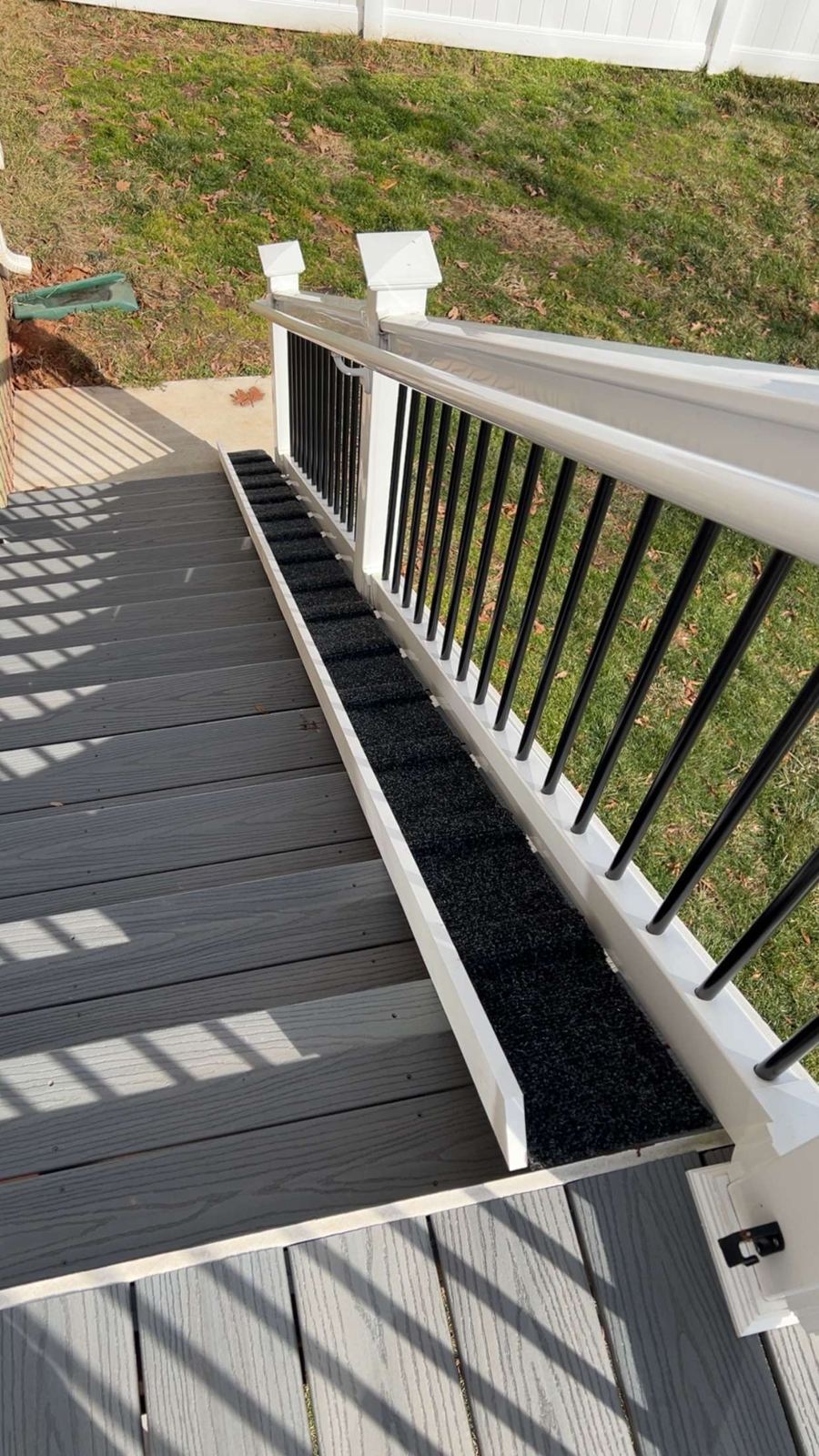 Finished PVC dachshund ramp with outdoor carpet beside deck stairs